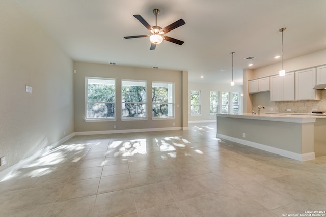 unfurnished living room with a wealth of natural light, sink, light tile patterned floors, and ceiling fan