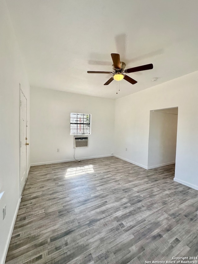 unfurnished room featuring a wall unit AC, ceiling fan, and wood-type flooring