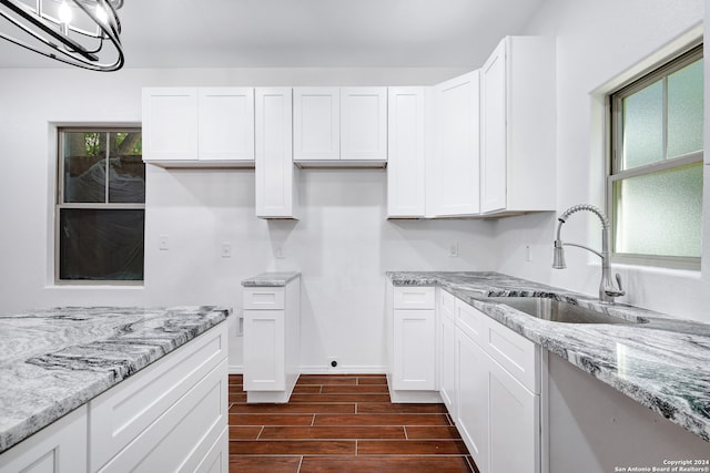 kitchen featuring light stone counters, sink, dark hardwood / wood-style flooring, white cabinetry, and a wall mounted AC