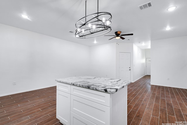 kitchen with hanging light fixtures, dark hardwood / wood-style floors, light stone counters, and white cabinetry