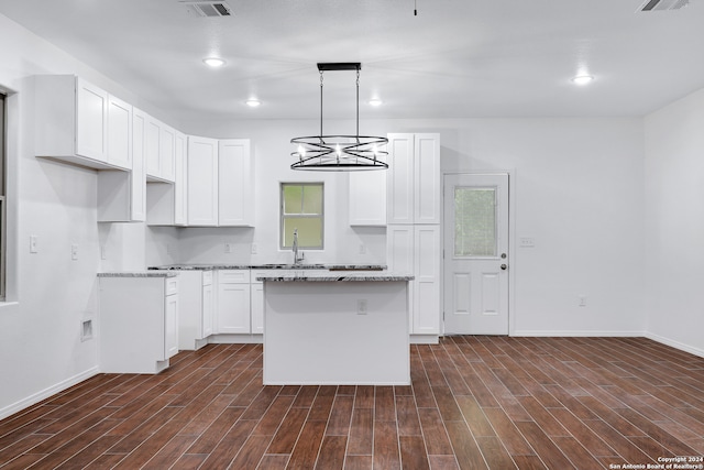 kitchen featuring a kitchen island, white cabinetry, decorative light fixtures, and dark wood-type flooring