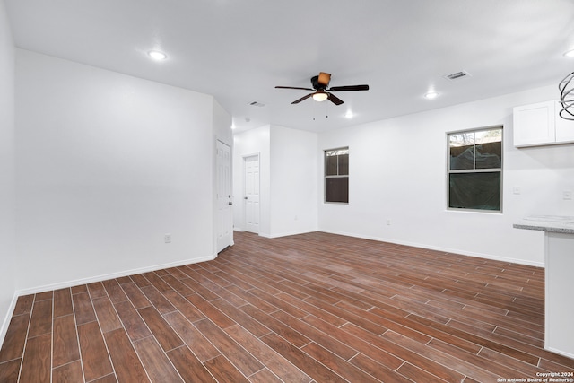 unfurnished living room featuring ceiling fan and dark wood-type flooring