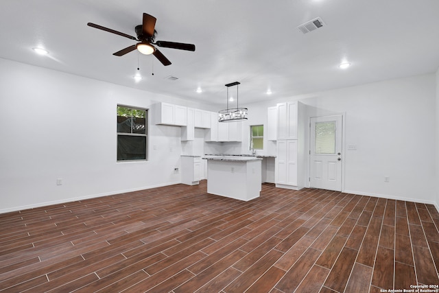 kitchen with ceiling fan with notable chandelier, a kitchen island, decorative light fixtures, dark hardwood / wood-style floors, and white cabinetry