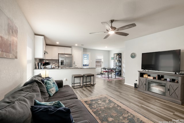 living room with light hardwood / wood-style floors, sink, and ceiling fan