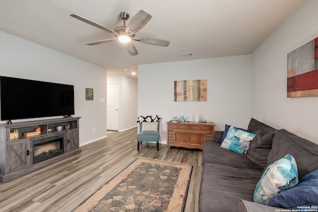 living room featuring ceiling fan, a fireplace, and hardwood / wood-style floors