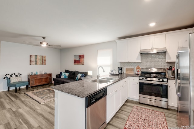 kitchen with stainless steel appliances, kitchen peninsula, white cabinets, and wood-type flooring