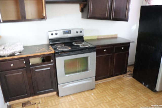 kitchen with stainless steel range with electric cooktop, light parquet flooring, ventilation hood, dark brown cabinets, and black refrigerator