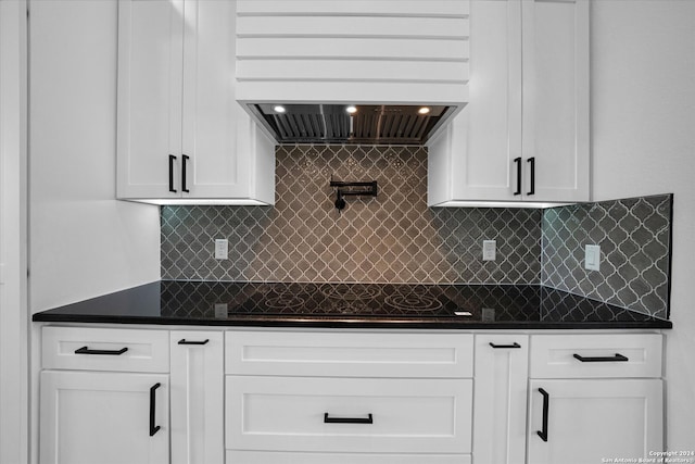 kitchen with white cabinetry, custom range hood, black electric stovetop, and backsplash