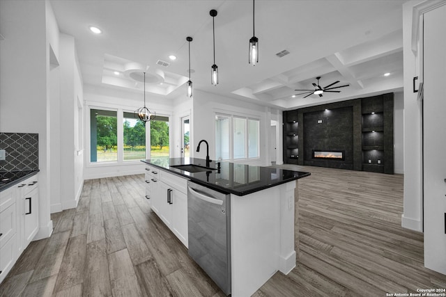 kitchen featuring stainless steel dishwasher, an island with sink, hanging light fixtures, and white cabinets