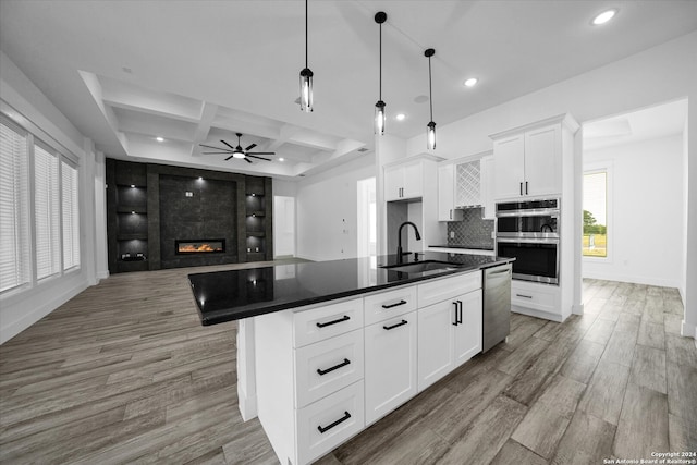 kitchen with white cabinets, a kitchen island with sink, sink, and coffered ceiling