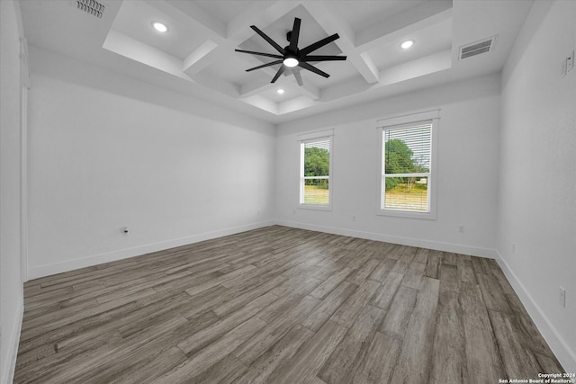 spare room featuring light hardwood / wood-style floors, beamed ceiling, coffered ceiling, and ceiling fan