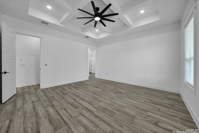 spare room featuring beam ceiling, coffered ceiling, light hardwood / wood-style flooring, and ceiling fan