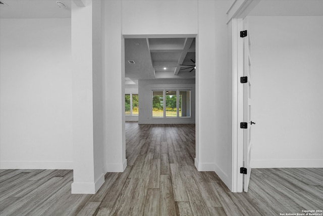 hall with beamed ceiling, coffered ceiling, and light hardwood / wood-style floors