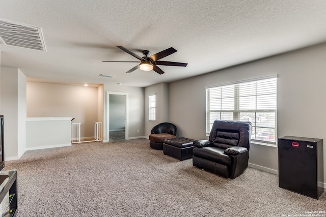 living area with a healthy amount of sunlight, light colored carpet, and a textured ceiling