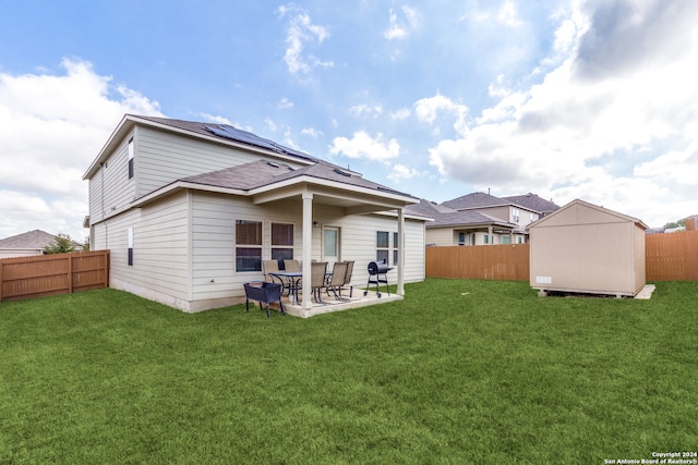 back of property with a lawn, solar panels, a patio, and a storage shed