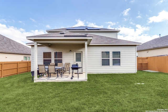 back of house with a lawn, a patio area, and solar panels