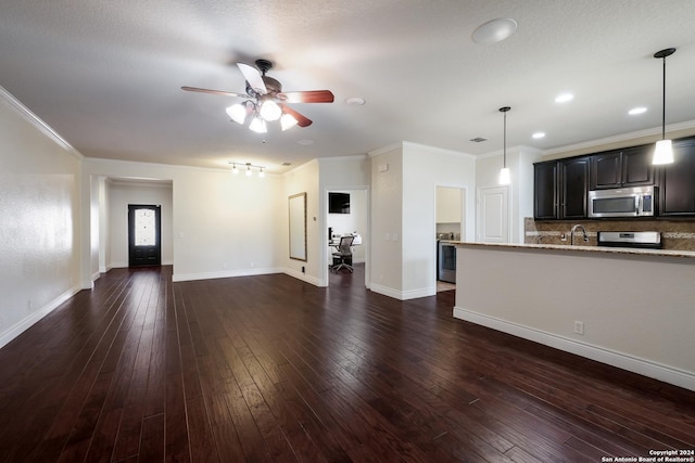 unfurnished living room featuring a ceiling fan, a sink, dark wood finished floors, baseboards, and ornamental molding