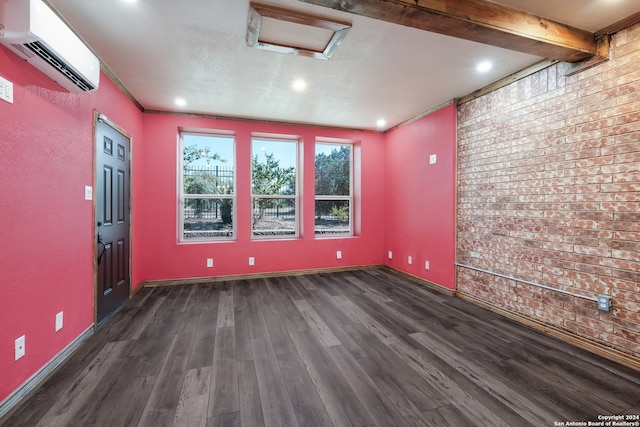 spare room with beam ceiling, brick wall, a wall mounted AC, and dark hardwood / wood-style floors