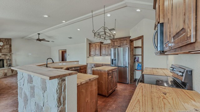 165 Lakeview Cir, La Vernia, TX 78121 - kitchen featuring vaulted ceiling with beams, a stone fireplace, stainless steel appliances, a center island with sink, and sink