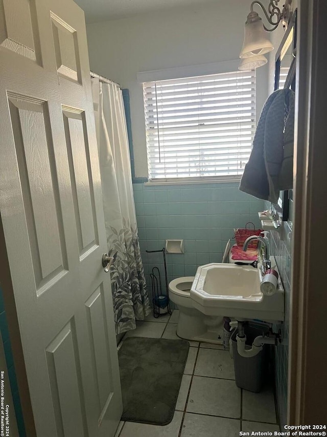 bathroom featuring tile patterned floors, a shower with curtain, sink, toilet, and tile walls