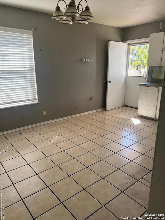 spare room featuring light tile patterned floors and an inviting chandelier