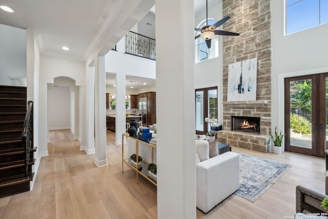 living room featuring ornamental molding, light hardwood / wood-style flooring, a fireplace, and a towering ceiling