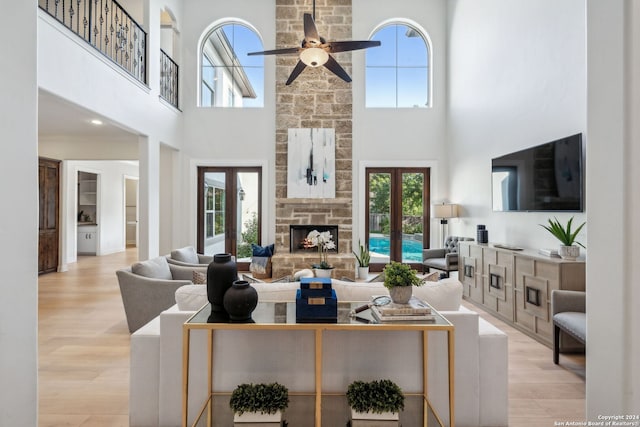 living room with light wood-type flooring, a towering ceiling, and plenty of natural light