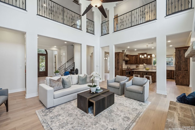 living room with a towering ceiling, light hardwood / wood-style flooring, and a chandelier