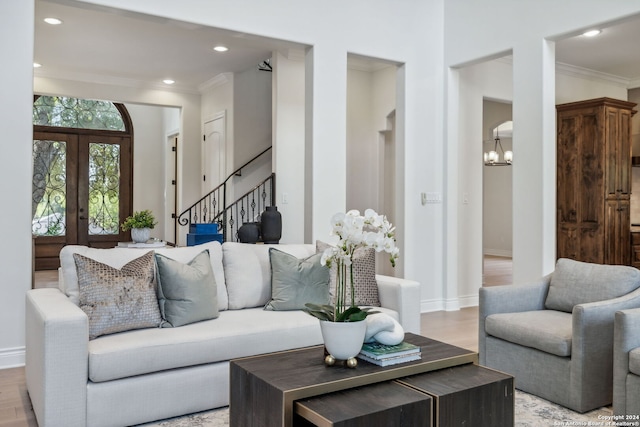 living room with an inviting chandelier, french doors, crown molding, and light hardwood / wood-style floors