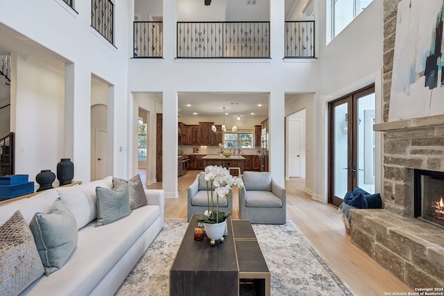 living room featuring a towering ceiling, a fireplace, and light hardwood / wood-style floors