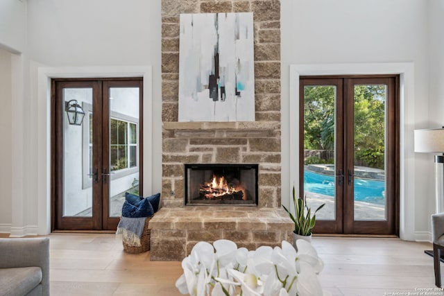 living room featuring french doors, a stone fireplace, and light hardwood / wood-style flooring