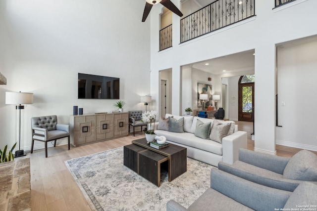 living room with light hardwood / wood-style floors, crown molding, a high ceiling, and ceiling fan