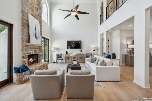 living room featuring light hardwood / wood-style floors, a healthy amount of sunlight, a towering ceiling, and ornamental molding