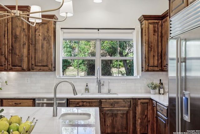 kitchen with dark brown cabinets, stainless steel appliances, sink, and backsplash