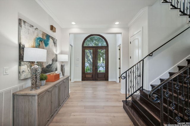 entrance foyer with crown molding, light wood-type flooring, and french doors