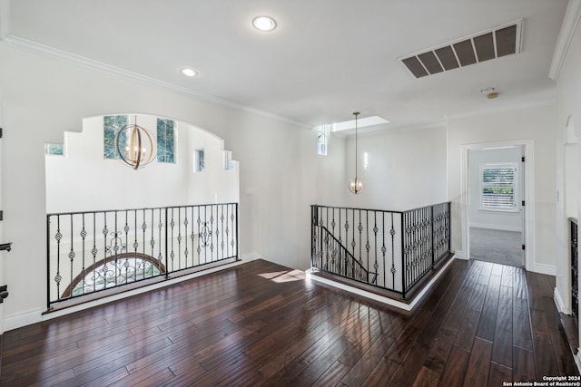 hallway with ornamental molding, a chandelier, and dark wood-type flooring