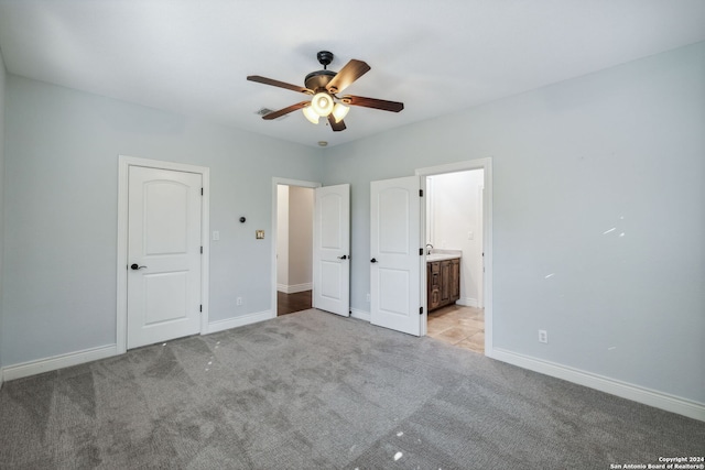 unfurnished bedroom featuring light carpet, ensuite bathroom, and ceiling fan