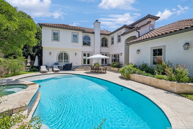 view of swimming pool featuring a patio area and an in ground hot tub