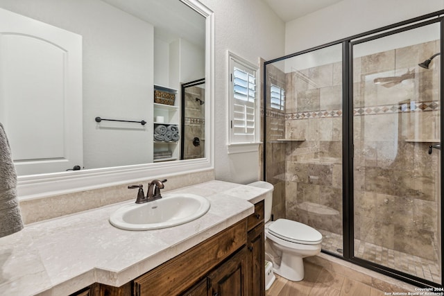 bathroom featuring vanity, hardwood / wood-style flooring, toilet, and walk in shower