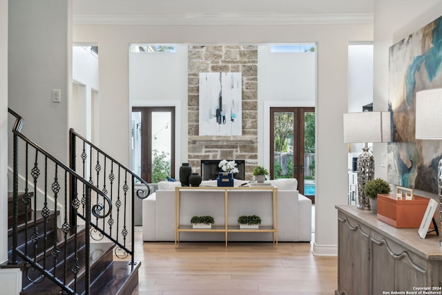 entrance foyer featuring french doors, light hardwood / wood-style floors, crown molding, and a fireplace