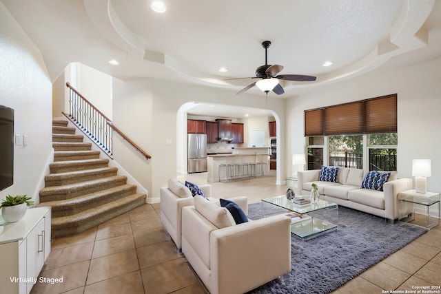 living area featuring a tray ceiling, light tile patterned floors, stairway, and recessed lighting