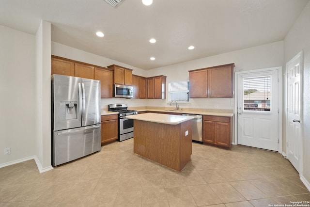 kitchen with sink, a kitchen island, stainless steel appliances, and light tile patterned floors