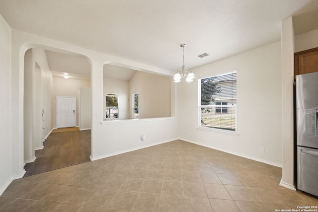 unfurnished dining area featuring light tile patterned flooring and an inviting chandelier