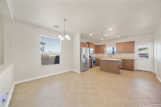 kitchen featuring stainless steel appliances, pendant lighting, light tile patterned floors, an inviting chandelier, and a center island