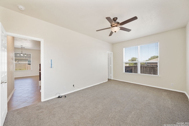 carpeted empty room with ceiling fan with notable chandelier