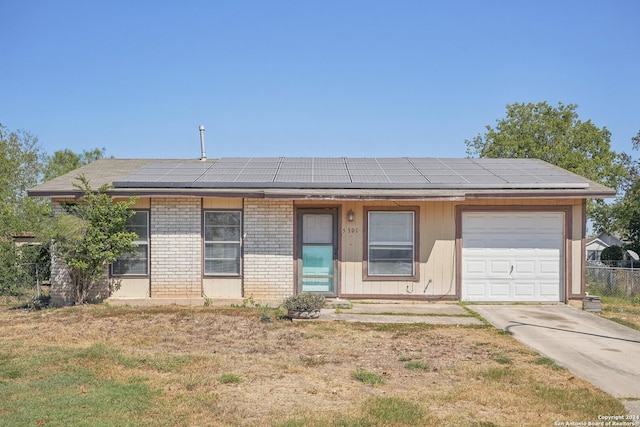 single story home with solar panels, a front lawn, and a garage