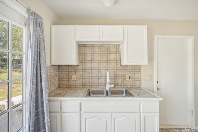 kitchen with white cabinets, sink, and backsplash