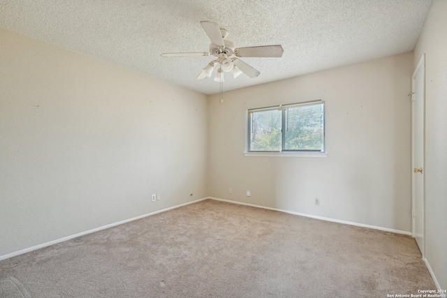 spare room featuring a textured ceiling, light colored carpet, and ceiling fan