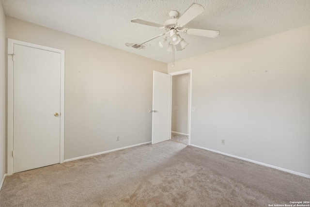 unfurnished room with a textured ceiling, light colored carpet, and ceiling fan