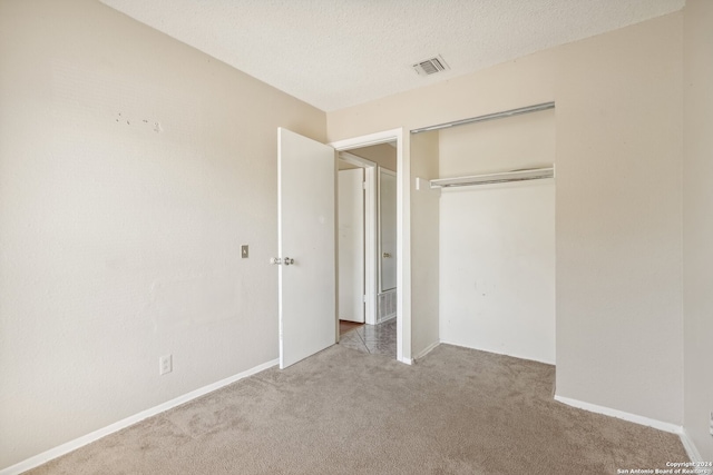 unfurnished bedroom featuring a closet, carpet flooring, and a textured ceiling